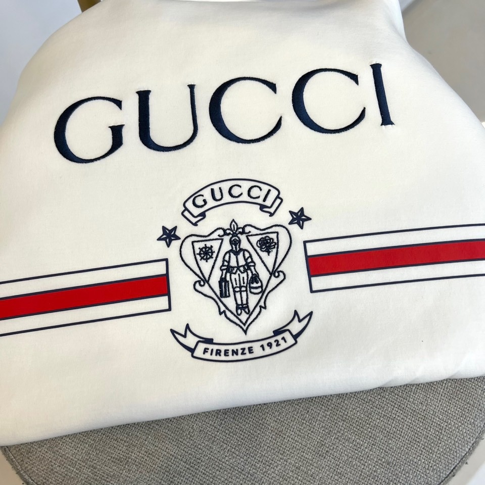 Gucc古驰、2025秋冬新品GU家经典徽章短袖T恤,这款白色T恤以简约设计展现品牌美学,胸前居中排列的
