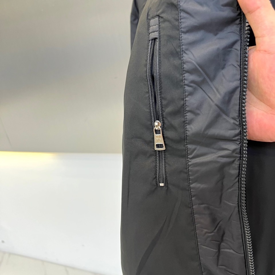 Mon蒙口、2025秋冬新品 男士连帽棉服夹克外套。这款黑色夹克采用立领连帽设计,帽檐与前襟配备银色金属