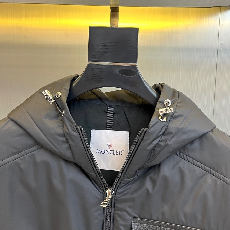 Mon蒙口、2025秋冬新品 男士连帽棉服夹克外套。这款黑色夹克采用立领连帽设计,帽檐与前襟配备银色金属