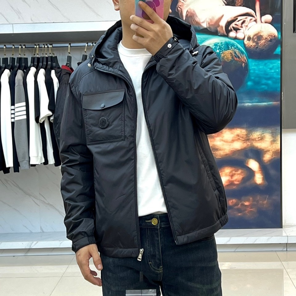 Mon蒙口、2025秋冬新品 男士连帽棉服夹克外套。这款黑色夹克采用立领连帽设计,帽檐与前襟配备银色金属