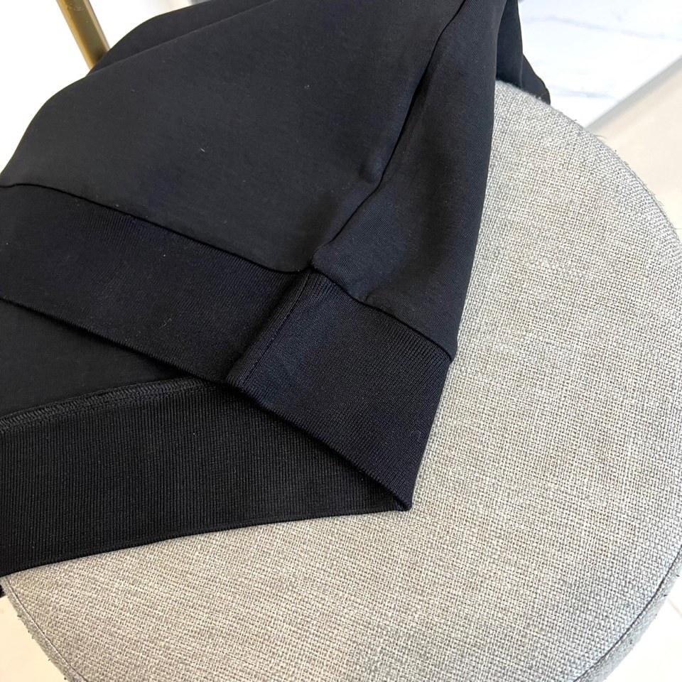 Prad普拉、2025秋冬新品 P家极简功能卫衣。这款黑色圆领卫衣采用简约立体剪裁，左臂处的银色拉链口袋