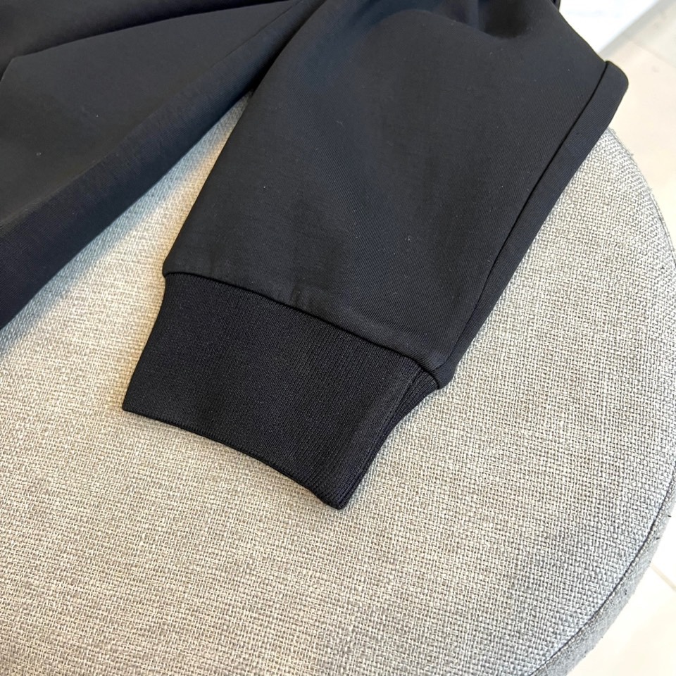 Prad普拉、2025秋冬新品 P家极简功能卫衣。这款黑色圆领卫衣采用简约立体剪裁，左臂处的银色拉链口袋