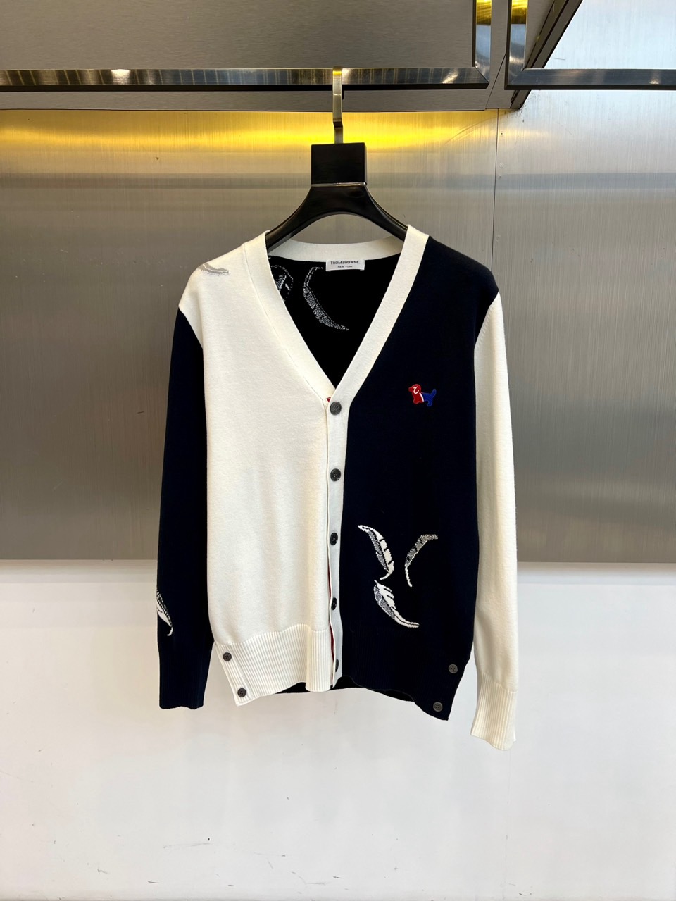 TB汤姆布朗、2025秋冬新品羊毛🦙针织开衫，以灰白拼接设计演绎童趣时尚美学。V领造型搭配黑色纽扣开合，