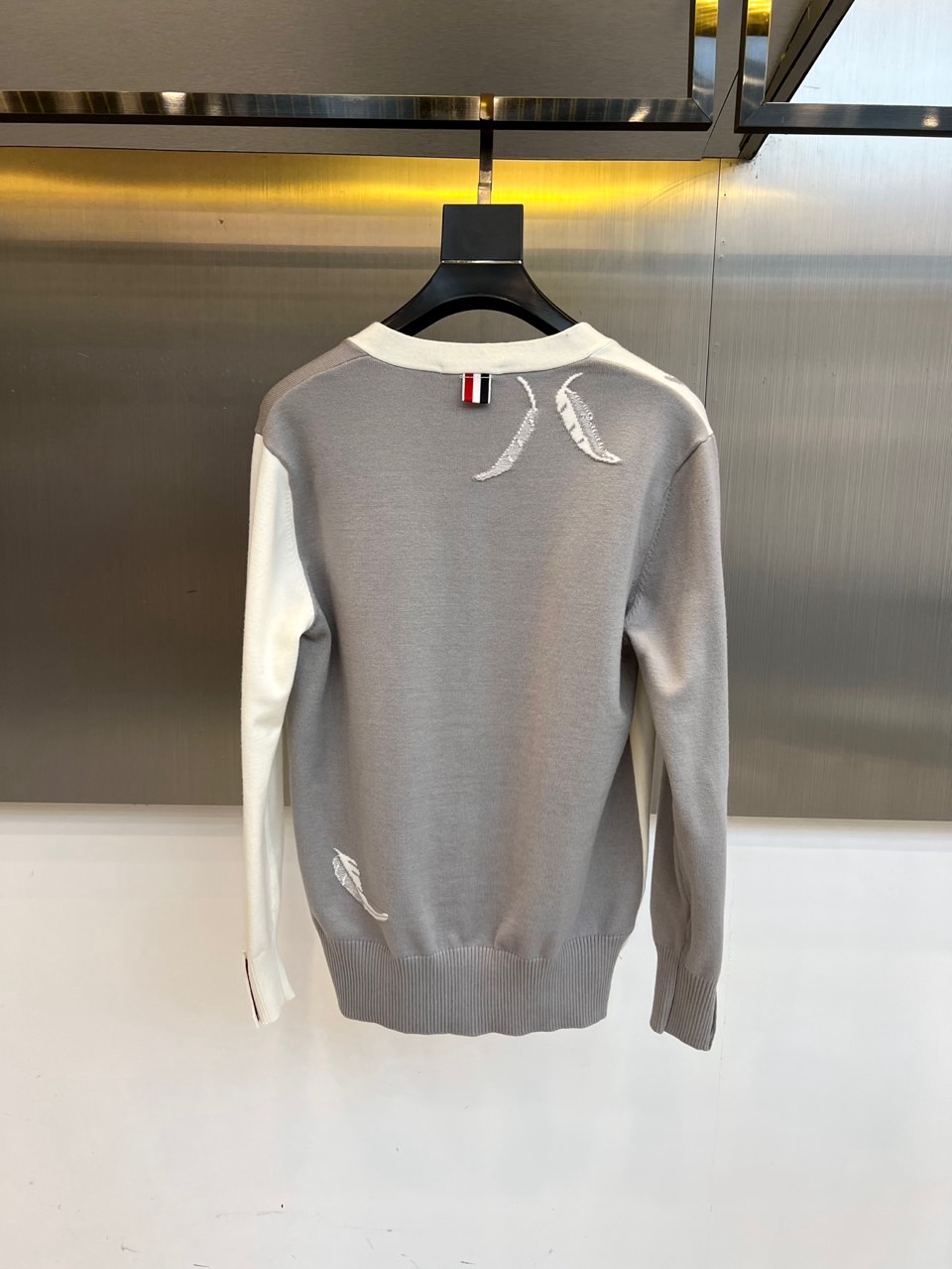 TB汤姆布朗、2025秋冬新品羊毛🦙针织开衫，以灰白拼接设计演绎童趣时尚美学。V领造型搭配黑色纽扣开合，