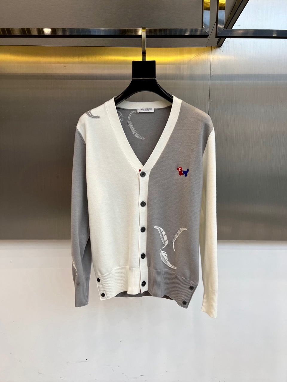TB汤姆布朗、2025秋冬新品羊毛🦙针织开衫，以灰白拼接设计演绎童趣时尚美学。V领造型搭配黑色纽扣开合，