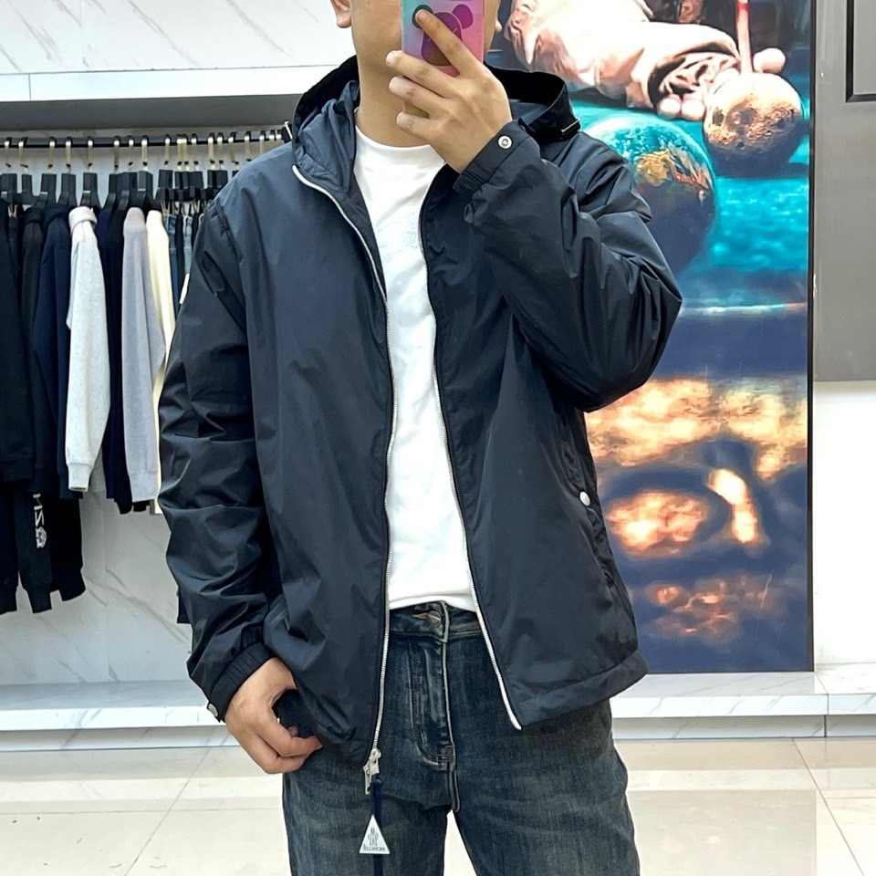 Mon蒙口、25s秋冬新品连帽夹克。冷调纯白如阿尔卑斯新雪，金属背景的钨丝灯光为衣身镀上暖金。拉开拉链乍