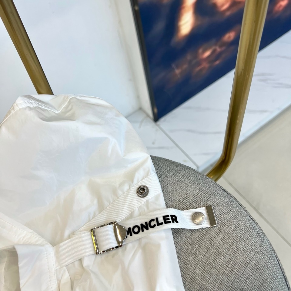 Mon蒙口、25s秋冬新品连帽夹克。冷调纯白如阿尔卑斯新雪，金属背景的钨丝灯光为衣身镀上暖金。拉开拉链乍