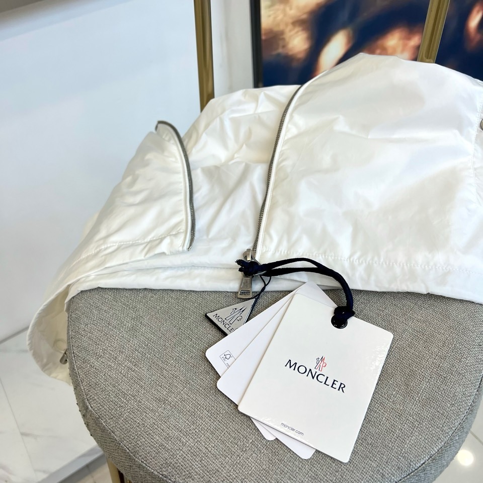 Mon蒙口、25s秋冬新品连帽夹克。冷调纯白如阿尔卑斯新雪，金属背景的钨丝灯光为衣身镀上暖金。拉开拉链乍