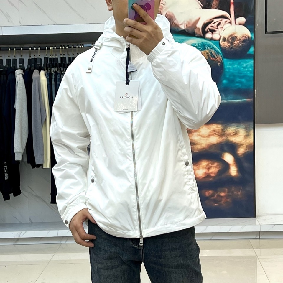 Mon蒙口、25s秋冬新品连帽夹克。冷调纯白如阿尔卑斯新雪，金属背景的钨丝灯光为衣身镀上暖金。拉开拉链乍