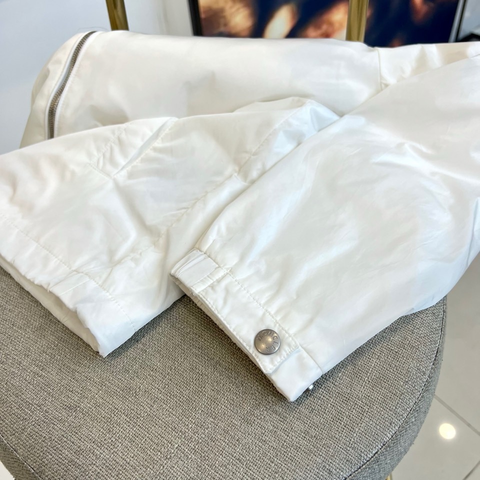 Mon蒙口、25s秋冬新品连帽夹克。冷调纯白如阿尔卑斯新雪，金属背景的钨丝灯光为衣身镀上暖金。拉开拉链乍