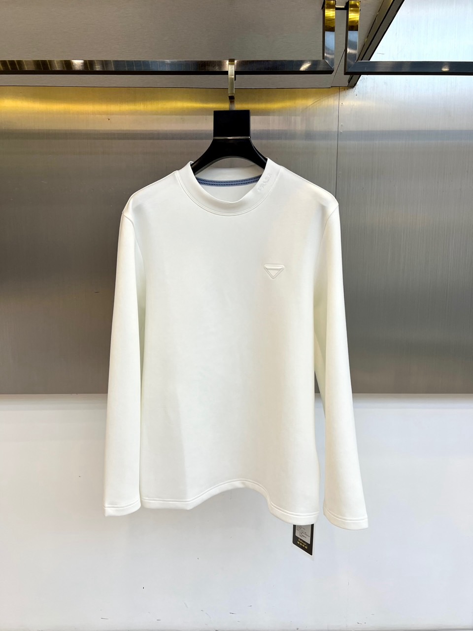 Prad普拉达、2025秋冬新品男士白色长袖T恤，以极简主义美学诠释现代奢华。本品采用320克莫代尔空气