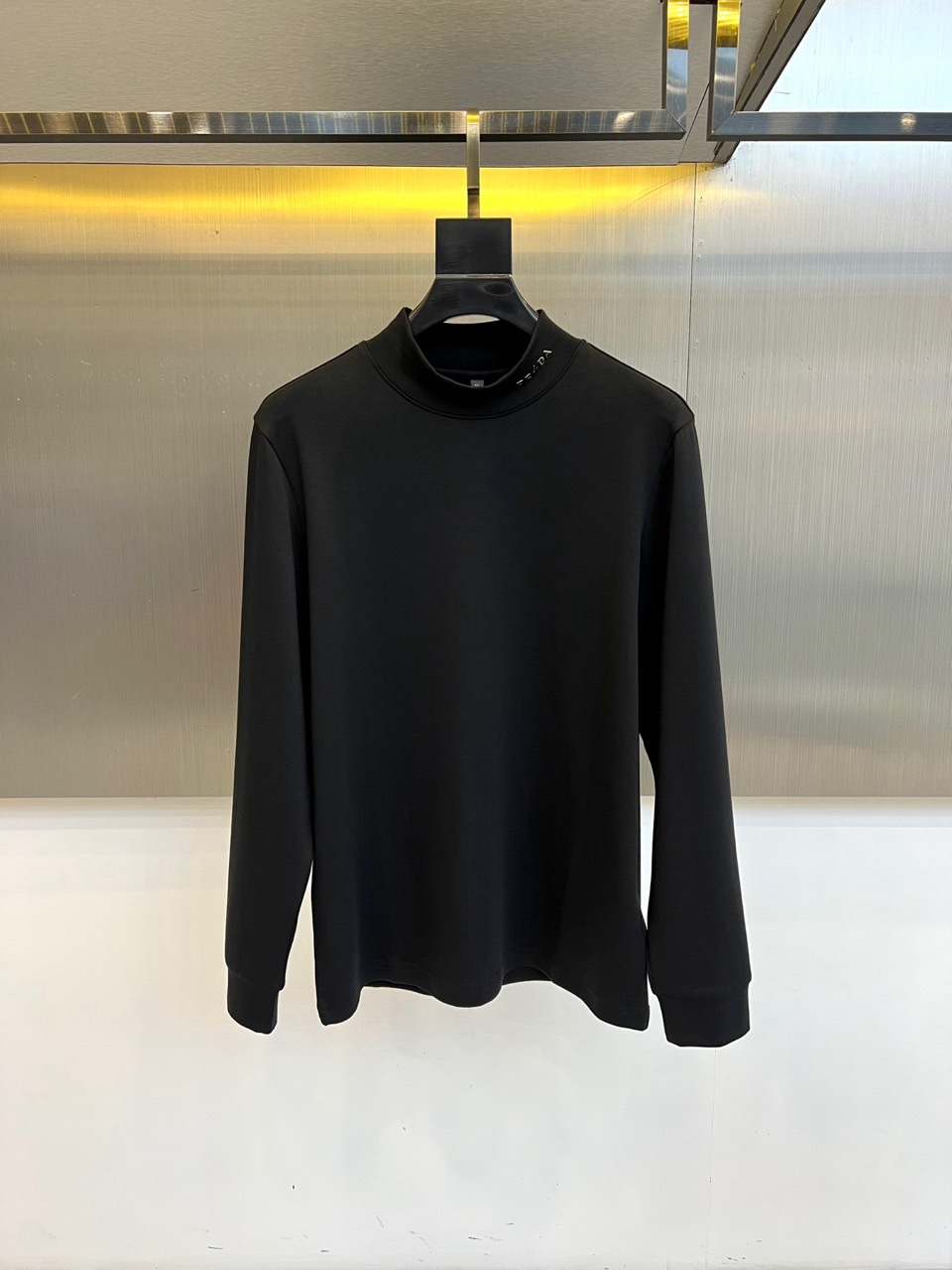 Prad普拉、2025秋冬新品 极简高领长袖羊毛🐑T恤打底衫。这款高领上衣采用立体剪裁设计，简约圆领搭配