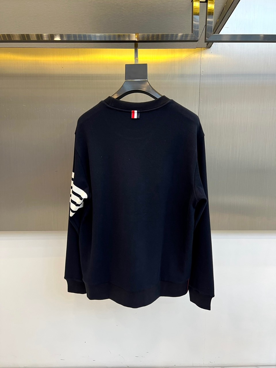 TB汤姆布朗、2025秋冬新品圆领卫衣，这款卫衣采用宽松休闲版型设计，左袖装饰四道白色条纹打造运动风尚。