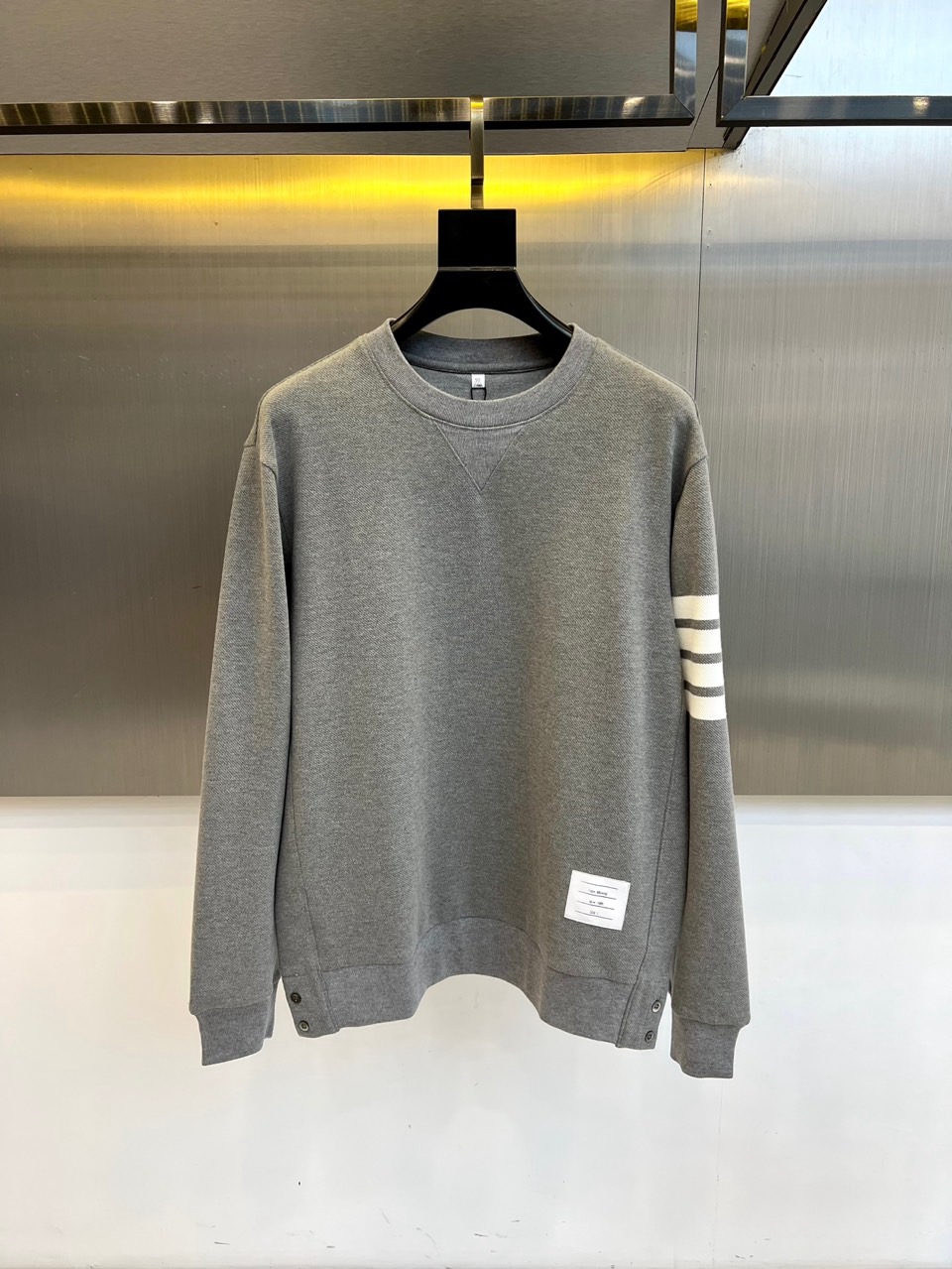 TB汤姆布朗、2025秋冬新品圆领卫衣，这款卫衣采用宽松休闲版型设计，左袖装饰四道白色条纹打造运动风尚。