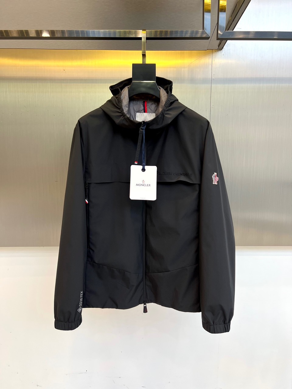 Mon蒙口、2025秋冬新品蒙口防风冲锋衣夹克，以醒目的橙红色调诠释户外机能美学。采用连帽设计搭配全拉链