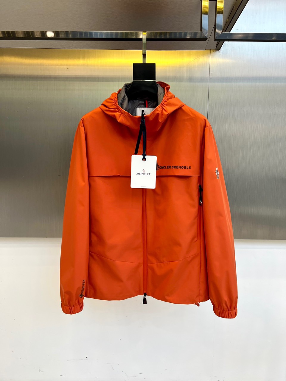 Mon蒙口、2025秋冬新品蒙口防风冲锋衣夹克，以醒目的橙红色调诠释户外机能美学。采用连帽设计搭配全拉链