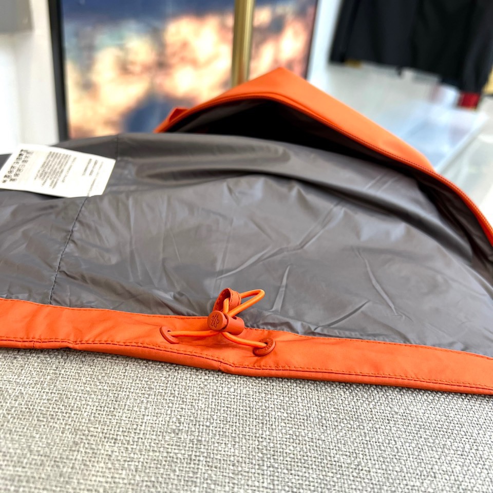 Mon蒙口、2025秋冬新品蒙口防风冲锋衣夹克，以醒目的橙红色调诠释户外机能美学。采用连帽设计搭配全拉链