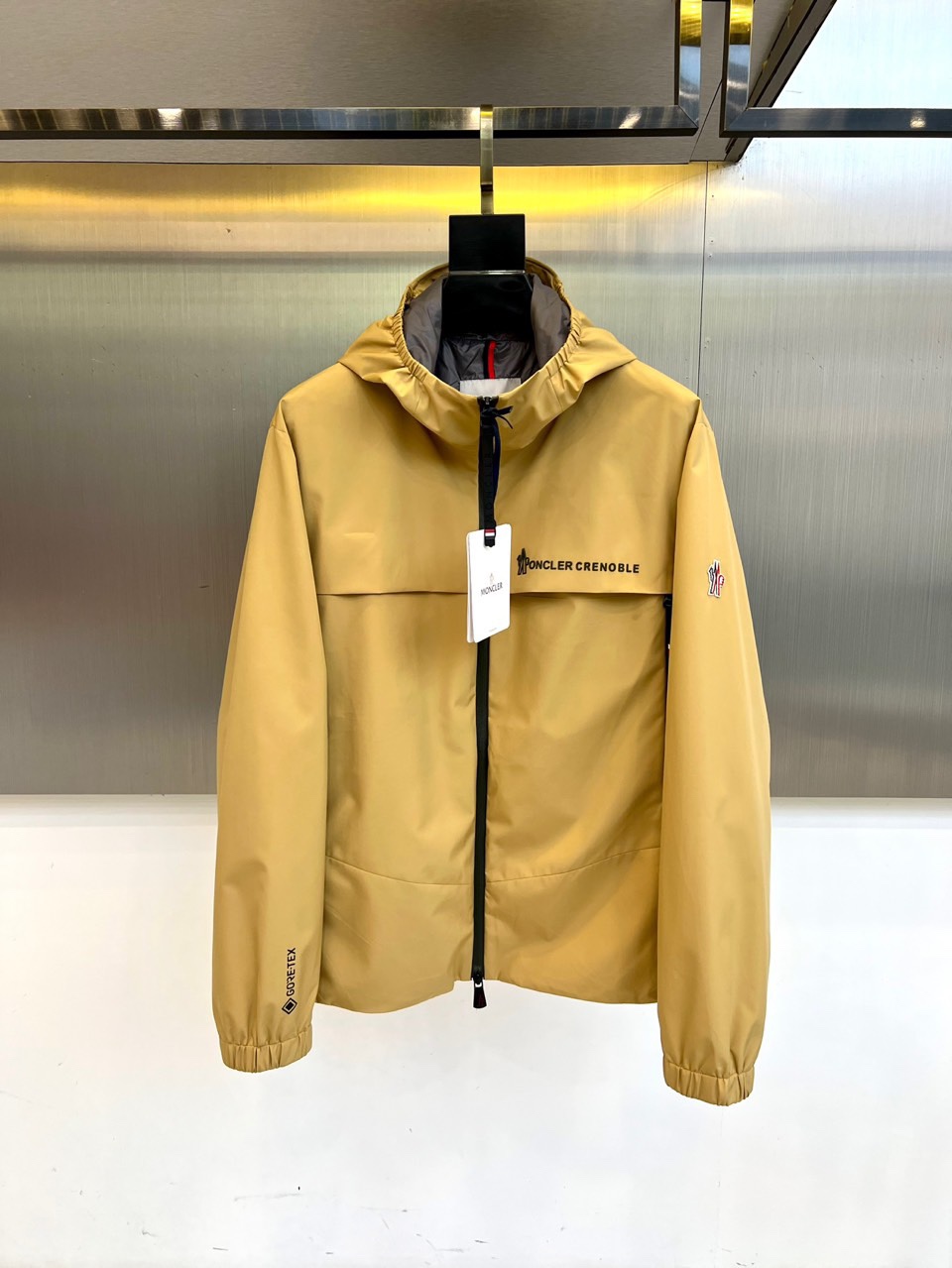 Mon蒙口、2025秋冬新品蒙口防风冲锋衣夹克，以醒目的橙红色调诠释户外机能美学。采用连帽设计搭配全拉链