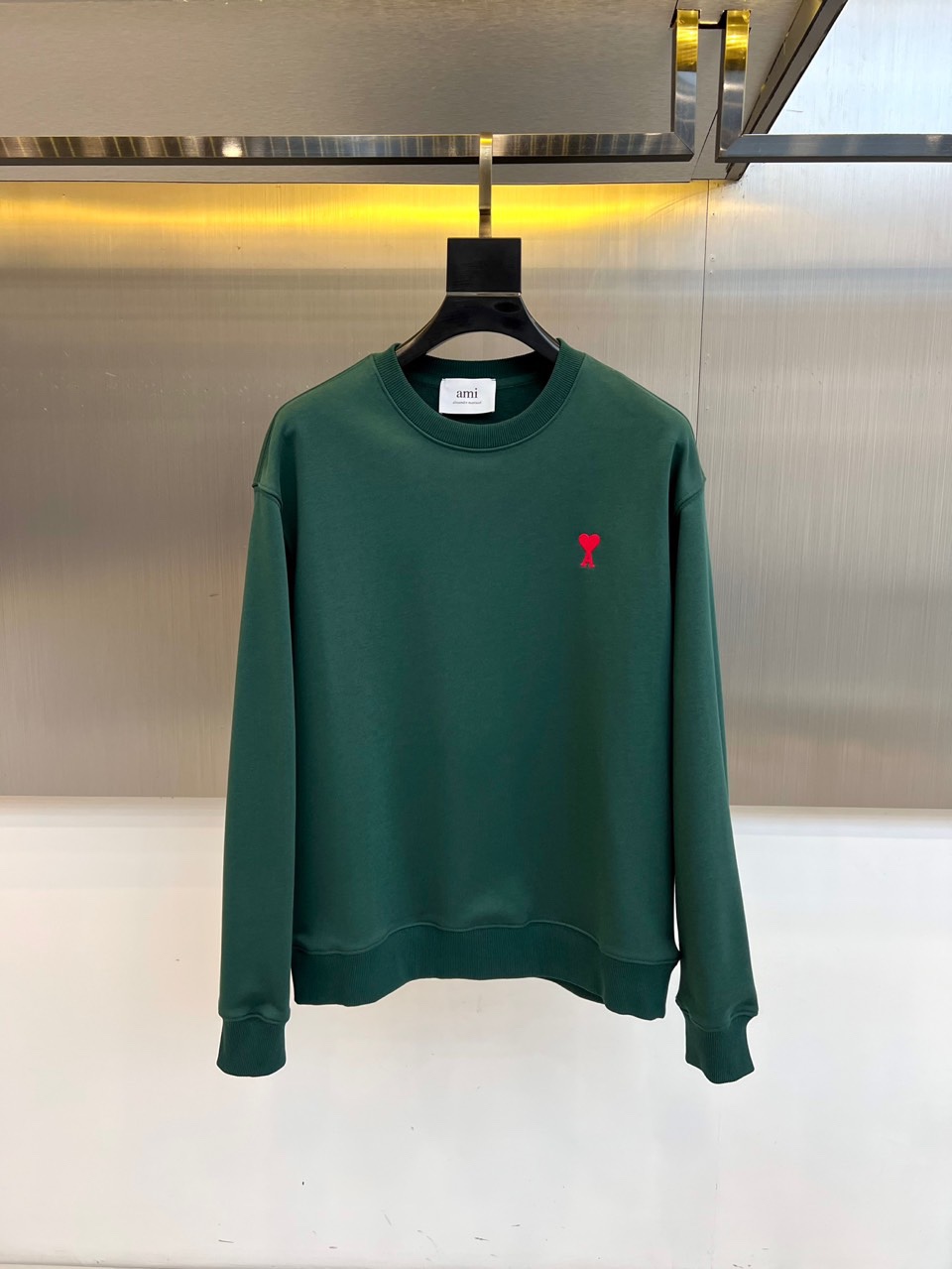 AMI 2025秋冬新品圆领卫衣，以纯净简约的白色为基调，打造秋冬清爽时尚感。胸前点缀品牌标志性红色爱心