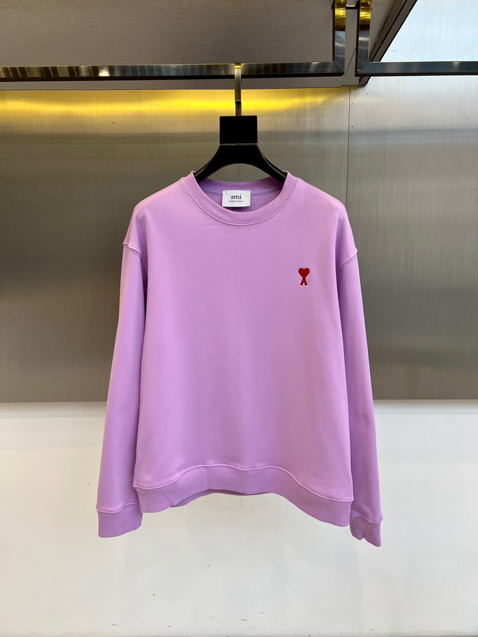 AMI 2025秋冬新品圆领卫衣，以纯净简约的白色为基调，打造秋冬清爽时尚感。胸前点缀品牌标志性红色爱心