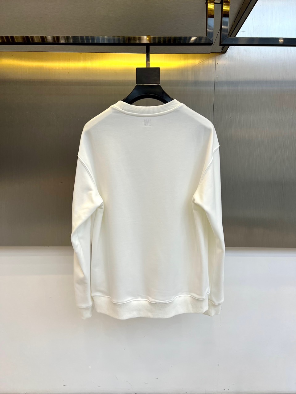 AMI 2025秋冬新品圆领卫衣，以纯净简约的白色为基调，打造秋冬清爽时尚感。胸前点缀品牌标志性红色爱心