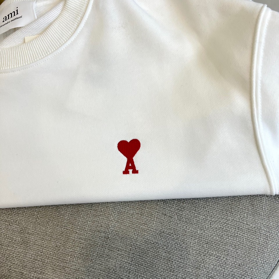AMI 2025秋冬新品圆领卫衣，以纯净简约的白色为基调，打造秋冬清爽时尚感。胸前点缀品牌标志性红色爱心