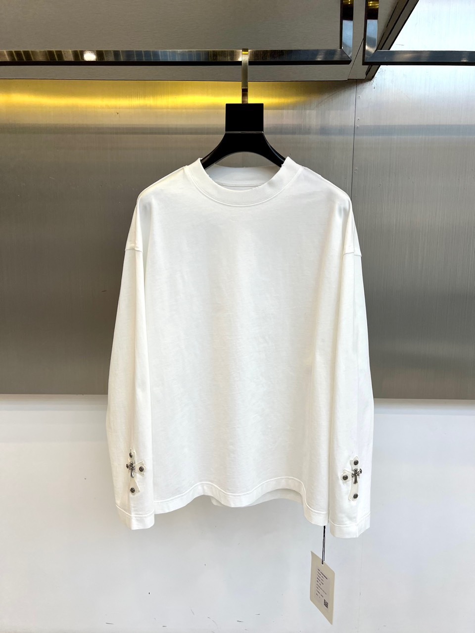 NO:545497,Ch Croxin and autumn and winter new men's long-sleeved T-shirts interpret modern street aesthetics with a pure white base. They adopt classic round neck design and loose cut. The metal-textured cross patterns are symmetrically decorated under the cuffs on both sides. Four rivets are precisely inlaid around each cross to create a visual impact that coexists with toughness and exquisiteness. Cotton fabric ensures skin-friendly and breathableness, and the draped texture and crisp style are perfectly balanced. Suitable for urban leisure, music scenes and trendy gatherings, you can wear it alone to show a simple style, or wear leather jackets to enhance the street style. The exquisite craftsmanship combines religious symbols with modern fashion, and through the clever combination of rivet details and metal elements, it becomes an iconic item in the wardrobe of trend enthusiasts that has both practical wear and attitude. S-XL (model 173, 143 catties upper body M size),, chrome  hearts,tees,t-shirt,leather jacket,alexander wang19860909Ch克罗心、秋冬新品男士长袖T恤,以纯净白色基底诠释现代街头美学.采用经典圆领设计与宽松剪裁,两侧袖口下方对称装饰金属质感十字架图案,每个十字架周围精密镶嵌四颗铆钉,打造硬朗与精致并存的视觉冲击.棉质面料确保亲肤透气性,垂坠质感与挺括版型完美平衡.适合都市休闲、音乐现场及潮流聚会场合,可单独穿着展现简约型格,或外搭皮衣强化街头风范.以精湛工艺将宗教符号与现代时尚融合,通过铆钉细节与金属元素的巧妙结合,成为潮流爱好者衣橱中兼具实穿性与态度的标志性单品.S-XL（模特173,143斤上身M码）,,chrome hearts,tees，t-shirt,leather jacket,alexander wang,Men's clothing