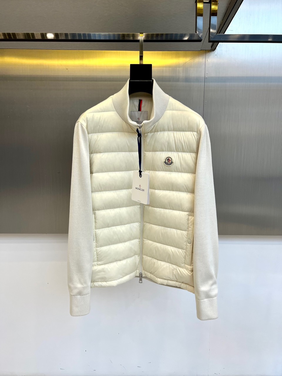 NO:545556,Mon veil (goosevelt), 25FW autumn and winter new knitted stitching down jacket. Horizontal quilting down is fluffy like fresh snow, dark knitted sleeves build functional rhythm. The stand collar lining is a glimpse of red and blue stripes, and the left chest embossing badge forms a visual password, flowing through the warm light and shadow layer of glacier cracks under the warm light of the metal wall. American standard goosevelt guardian Polyester fiber shell builds a windproof barrier USA-certified goosevelt filling, each tuft is the temperature memory of the Alps Three-mode intelligent switching system 1. Standal collar closure + knitted cuff tightening = extreme cold defense form 2. Zipper half open reveals red and blue stripes = urban wandering mode 3. Horizontal quilting will present a three-dimensional embossing effect 1-5 (model 173, 143 catties upper body 2 yards), Moncler, down  Jacket,alexander wang19860909Mon蒙口（鹅绒）、25FW秋冬新品针织拼接羽绒服 横向绗缝羽绒如新雪蓬松,深色针织袖管构筑机能韵律.立领内衬惊鸿一瞥的红蓝条纹,与左胸浮雕徽章构成视觉密码,在金属墙面暖光下流转冰川裂隙般的光影层次. 美国标准鹅绒守护 聚酯纤维外壳构筑防风屏障 USA-认证鹅绒填充,每簇绒朵都是阿尔卑斯山的温度记忆 三模智能切换系统 1. 立领闭合+针织袖口收紧=极寒防御形态 2. 拉链半开露出红蓝条纹=都市漫游模式 3. 横向绗缝会呈现立体浮雕效果 1-5码（模特173,143斤上身2码）,,Moncler,down jacket,alexander wang,Men's clothing