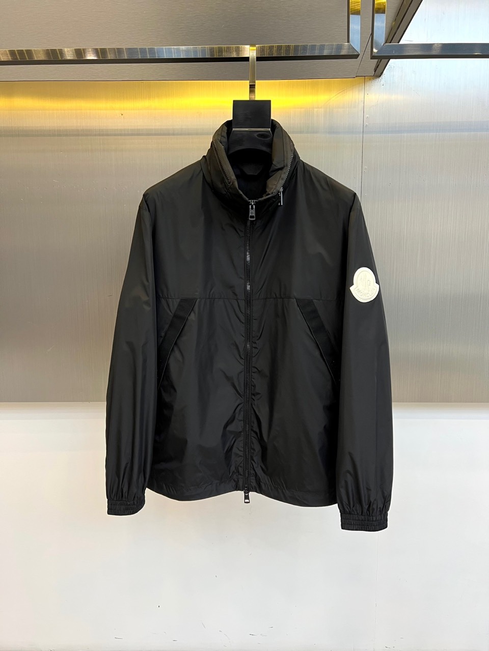 NO:545607,MON cover and autumn and winter new jacket jackets interpret modern urban functional aesthetics with minimalist stand-up collar design. They use a smooth zipper opening and closing system and are tailored with straight lines to create a neat outline. The left sleeve is embroidered with an iconic white brand badge, which shows the brand identity with simple embroidery. It is made of high-performance windproof fabric, which combines soft touch and excellent protection. Its style is perfectly balanced, practical functions and fashionable texture, and the pure black tone presents a low-key and luxurious temperament. The stand-up collar design enhances windproof attributes. It can be matched with casual pants to interpret urban sports style, and can also be layered to cope with changing weather. This jacket has exquisite craftsmanship and iconic details, becoming an ideal choice for traveling through urban life in autumn and winter. Size 1-5 (model 173, 143 catties upper body 2 sizes), Moncler, jackets & coats, jackets & coats, alexander wang19860909MON蒙口、秋冬新品夹克外套,以极简立领设计诠释现代都市机能美学.采用顺滑拉链开合系统,搭配直线条剪裁塑造利落轮廓.左袖点缀标志性白色品牌徽章,以简约刺绣工艺彰显品牌身份.选用高性能防风面料打造,兼具柔软触感与出色防护性能.其风格完美平衡实用功能与时尚质感,纯黑基调呈现低调奢华气质,立领设计增强防风属性.既能搭配休闲裤装演绎都市运动风,亦可层叠穿搭应对多变天气.这件夹克以精湛工艺与标志性细节,成为秋冬季节穿梭于城市生活的理想选择.1-5码（模特173,143斤上身2码）,,Moncler,jackets & coats,jackets & coats,alexander wang,Men's clothing