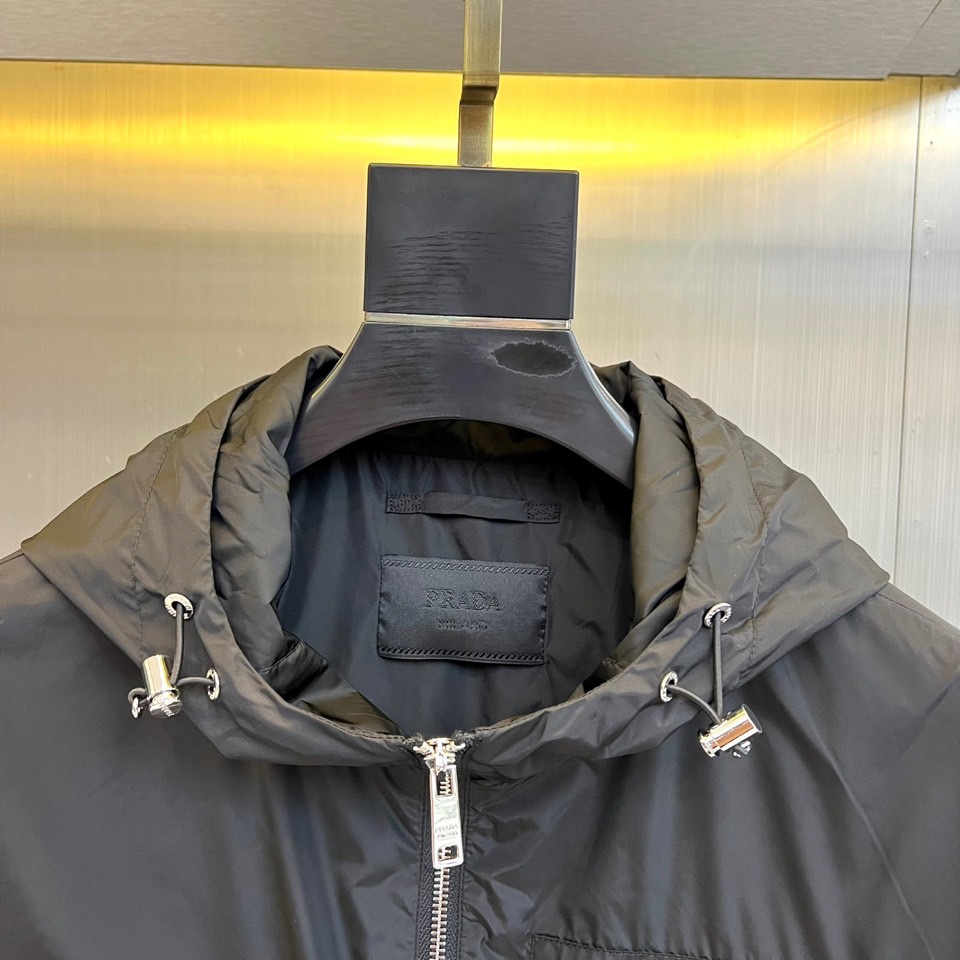 Prad普拉、2025秋冬新品黑色连帽夹克外套，以极简设计诠释现代都市美学。采用品牌标志性的高科技尼龙面