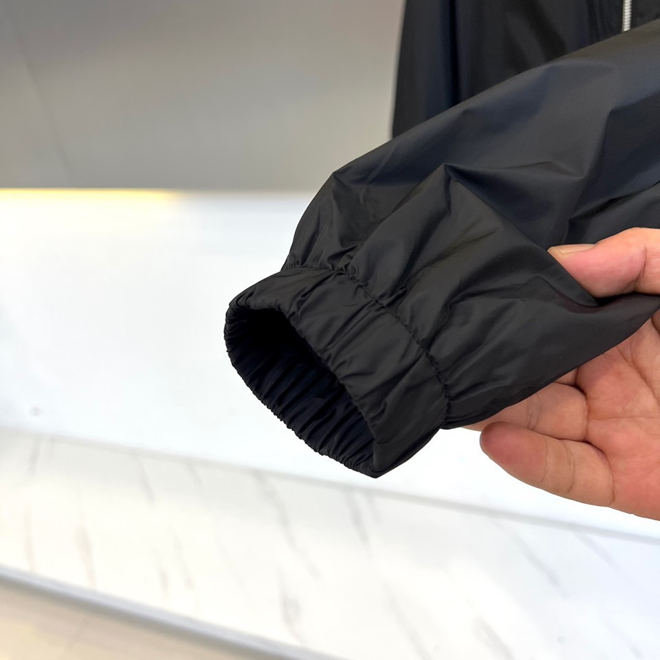 Prad普拉、2025秋冬新品黑色连帽夹克外套，以极简设计诠释现代都市美学。采用品牌标志性的高科技尼龙面