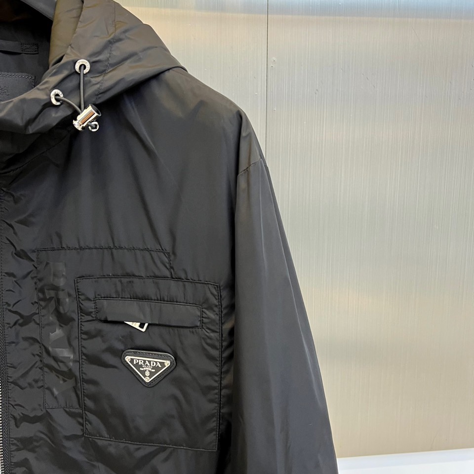 Prad普拉、2025秋冬新品黑色连帽夹克外套，以极简设计诠释现代都市美学。采用品牌标志性的高科技尼龙面