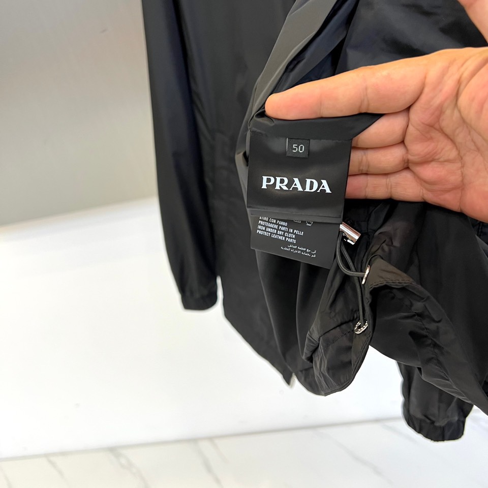 Prad普拉、2025秋冬新品黑色连帽夹克外套，以极简设计诠释现代都市美学。采用品牌标志性的高科技尼龙面