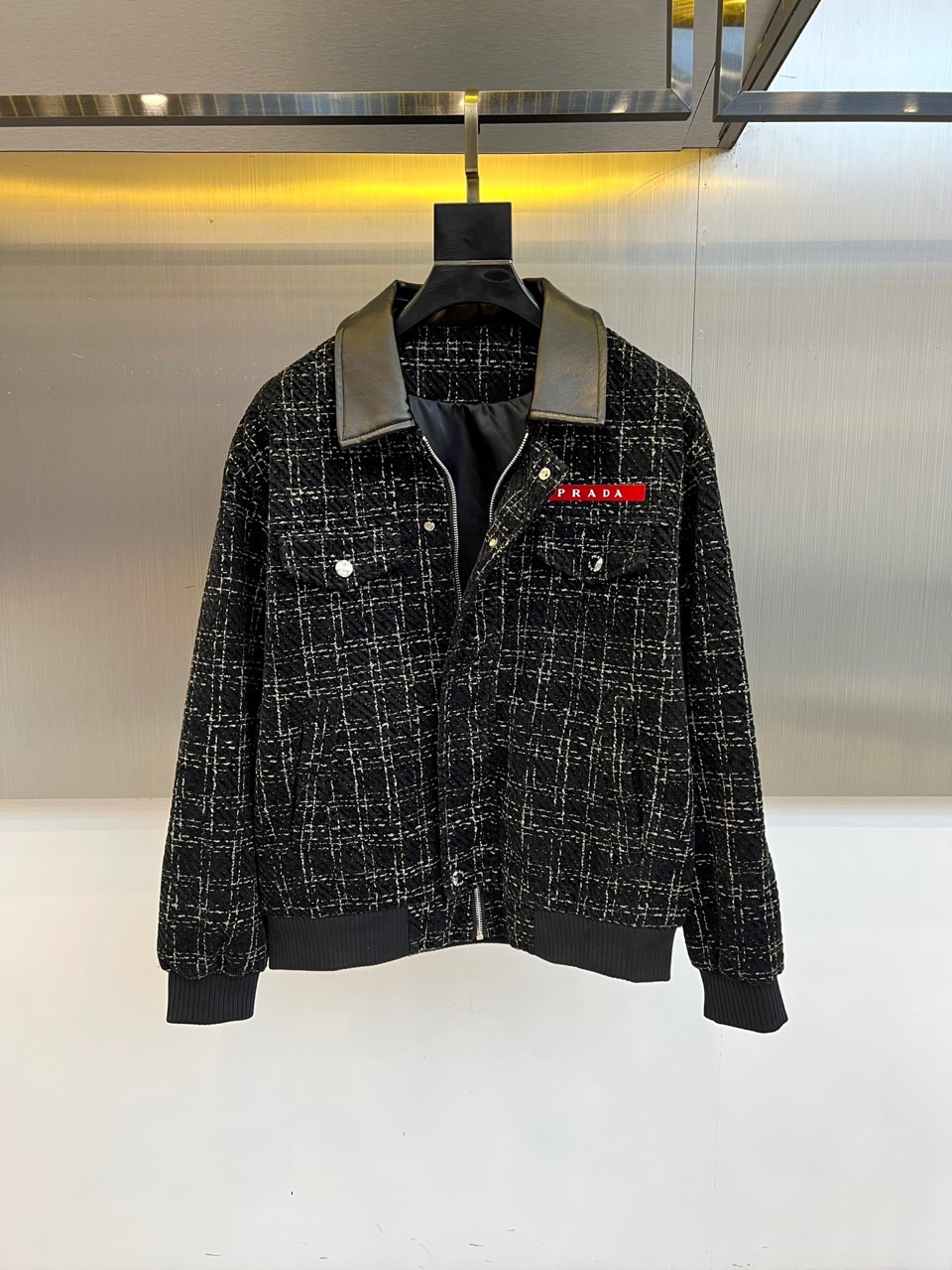 NO:564072,Prada, the new men's jacket for autumn and winter, redefines luxury outerwear for autumn and winter with the brand's iconic retro aesthetics and modern design language. This product is made of gray and black intertwined tweed plaid fabric, showing a three-dimensional texture and high-end texture. The classic lapel design is made of black leather  Made of high-quality material, it is in sharp contrast with the plaid main body. The chest is decorated with eye-catching red PRADA brand logo embroidery, and the symmetrical diagonal pockets on both sides are decorated with metal buttons, taking into account practical functions and exquisite details. The cuffs and hem are designed with dark gray ribbed edges to enhance protection.  Warmth and fit. The tailoring is slim and neat, ensuring a straight and stylish fit. This jacket perfectly combines retro style and modern fashion. It can be paired with formal pants to show a business casual style, or it can be paired with casual pants to create an urban modern look. Prada uses exquisite craftsmanship and innovative design to combine  The traditional tweed fabric has been sublimated into a fashion item with both luxurious texture and practicality, becoming an indispensable classic in men's wardrobe in autumn and winter. 48-56 (model weighs 173,143 pounds, upper body size 50),, prada, prada, jackets   & coats,jackets & coats,alexander wang19860909Prad普拉达、秋冬新品男士夹克外套,以品牌标志性的复古美学与现代设计语言重新定义秋冬奢华外套.本品采用灰黑交织的粗花呢格纹面料,呈现立体纹理与高级质感.经典翻领设计选用黑色皮质材质打造,与格纹主体形成鲜明对比.胸前饰有醒目的红色PRADA品牌标识刺绣,两侧对称斜插口袋配以金属纽扣装饰,兼顾实用功能与精致细节.袖口及下摆采用深灰色罗纹收边设计,增强保暖性与贴合度.剪裁修身利落,确保穿着挺拔有型.这款夹克完美融合复古格调与现代时尚感,既可搭配正装裤展现商务休闲风格,亦能与休闲裤打造都市摩登造型.普拉达以精湛工艺与创新设计,将传统粗花呢面料升华为兼具奢华质感与实穿性的时尚单品,成为秋冬男士衣橱中不可或缺的经典之作.48-56（模特173,143斤上身50码）,,prada,prada,jackets & coats,jackets & coats,alexander wang,Men's clothing