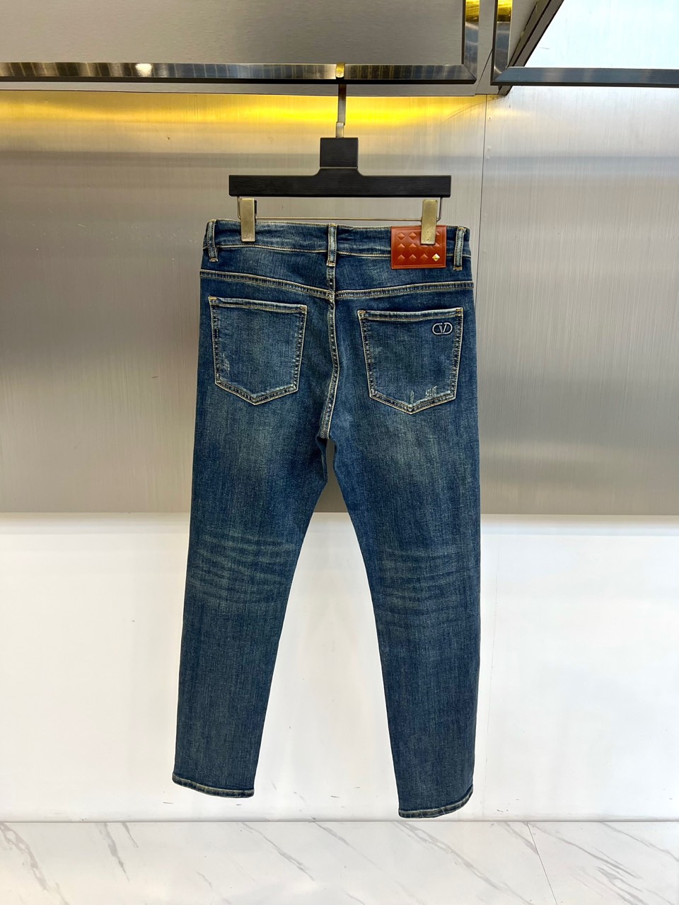 VT华伦天奴、2025秋冬新品深蓝色牛仔裤，以经典丹宁重塑现代奢华美学。后袋上方装饰标志性棕色菱格纹皮革