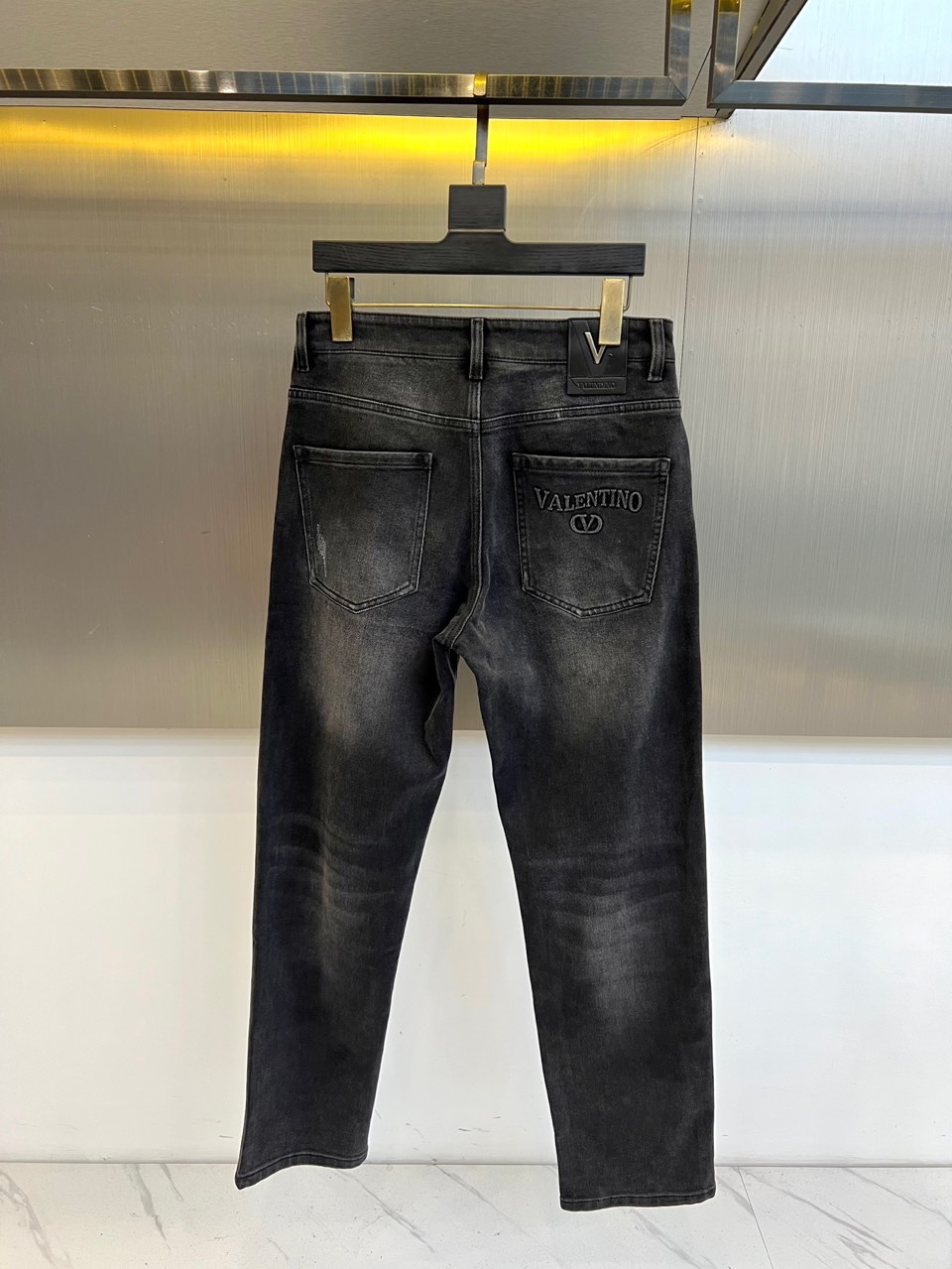 VT华伦天奴、2025秋冬新品华伦天奴标志刺绣牛仔裤，这款深灰色牛仔裤采用品牌标志性设计语言，后袋处以立