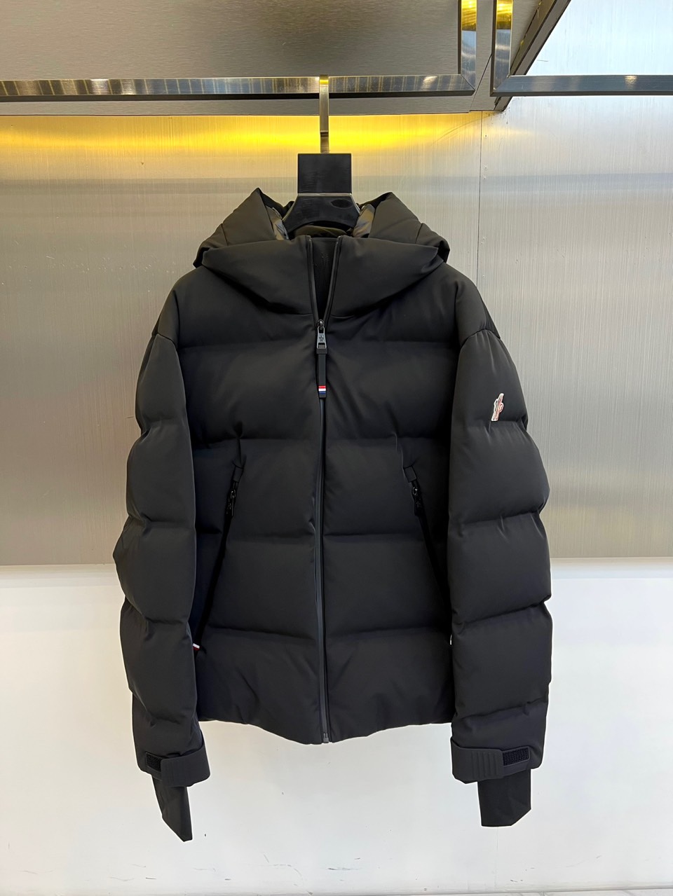 Mon蒙口、2025秋冬新品 MONCLER滑雪羽绒服。黑色长款设计通过精准的绗缝线条划分出立体块状结构