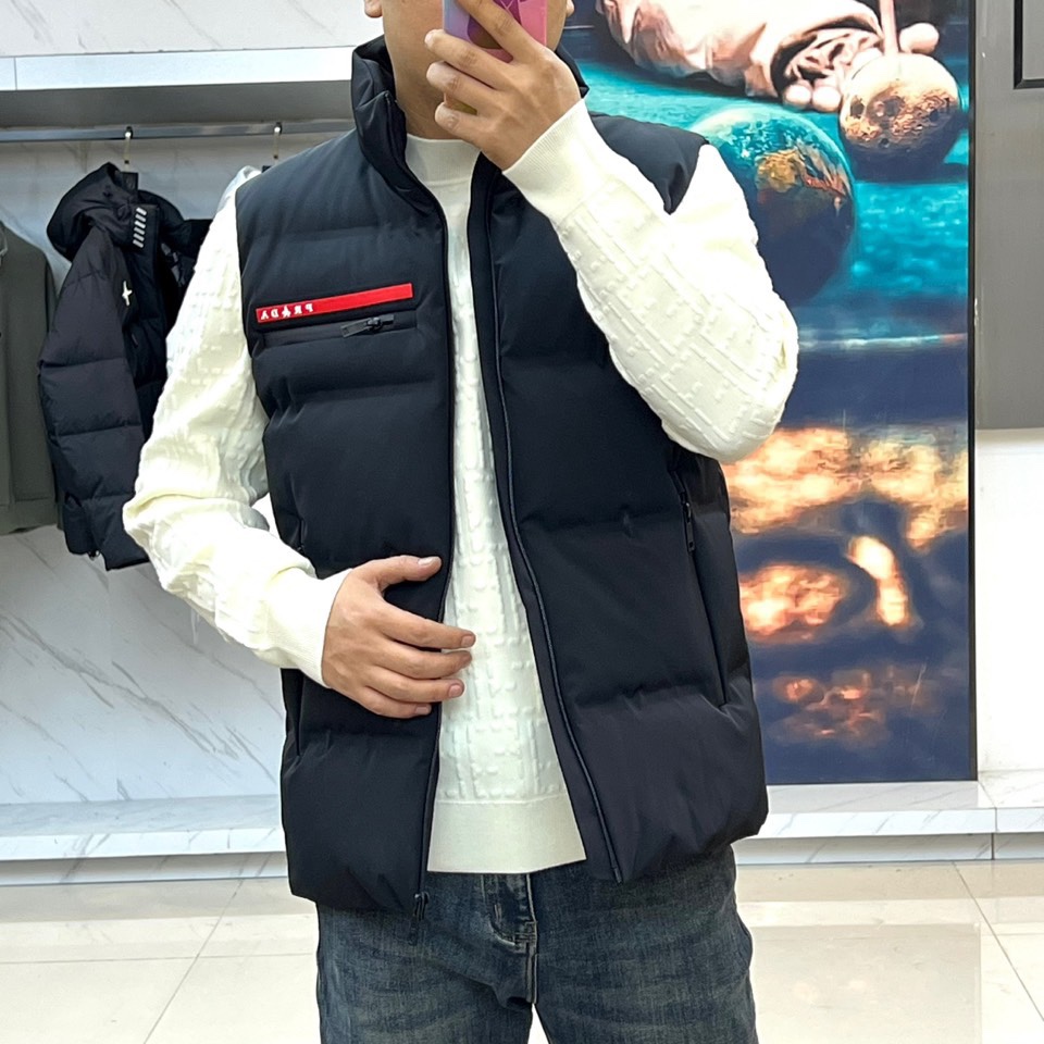 Prad普拉达、2025秋冬新品 PRADA机能风羽绒马甲。立领设计搭配无袖剪裁，正面配置黑色顺滑拉链开