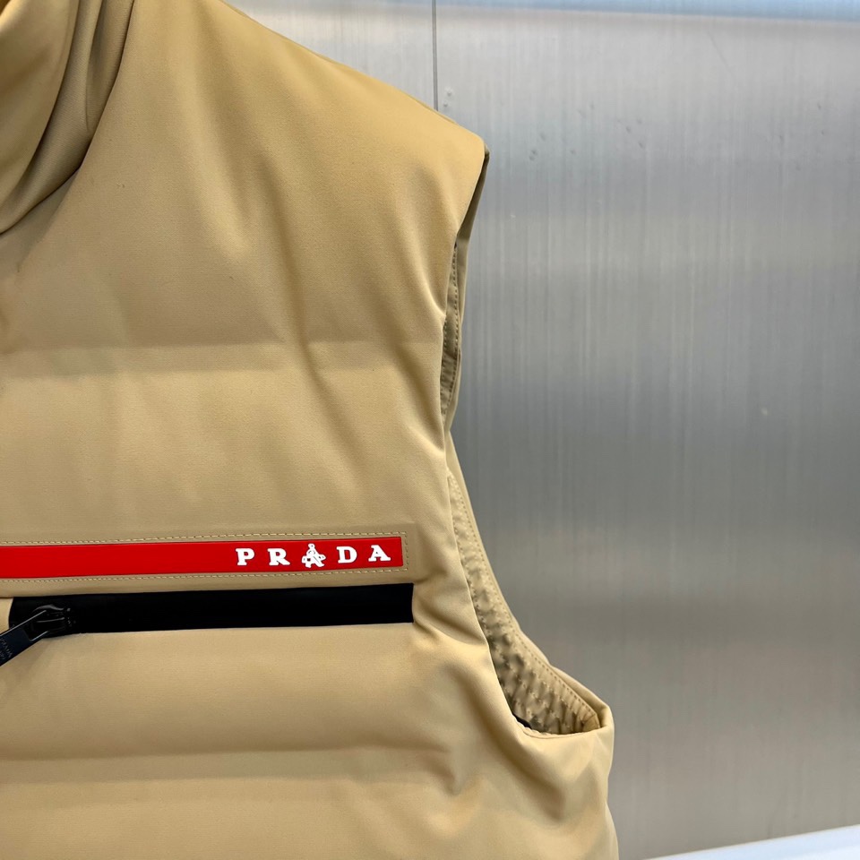 Prad普拉达、2025秋冬新品 PRADA机能风羽绒马甲。立领设计搭配无袖剪裁，正面配置黑色顺滑拉链开