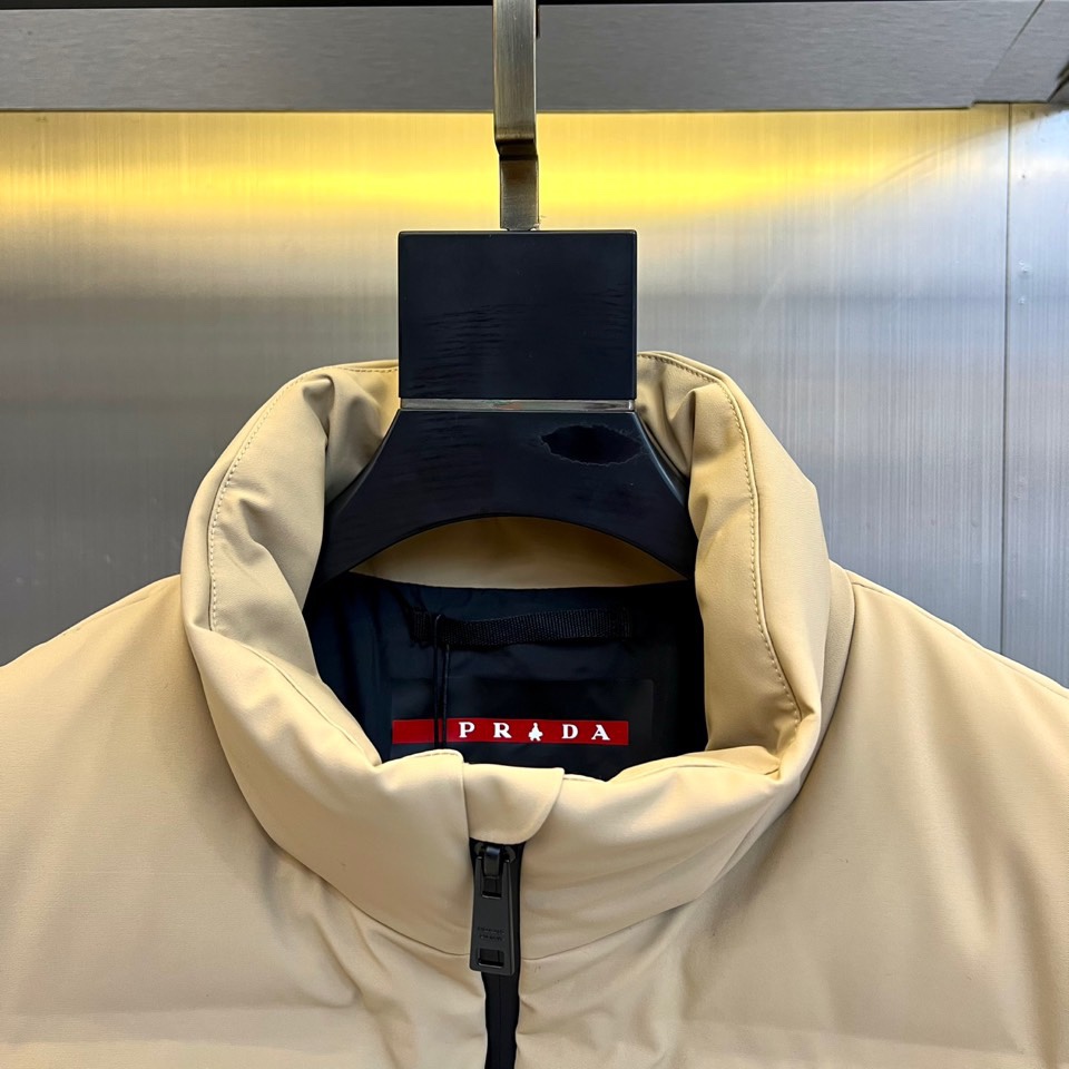 Prad普拉达、2025秋冬新品 PRADA机能风羽绒马甲。立领设计搭配无袖剪裁，正面配置黑色顺滑拉链开
