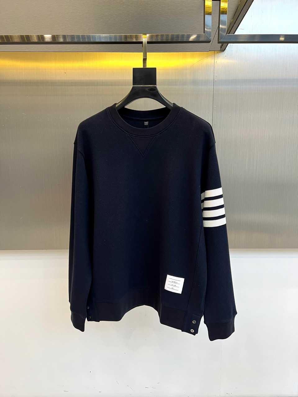 TB汤姆布朗、2025秋冬新品圆领卫衣，这款卫衣采用宽松休闲版型设计，左袖装饰四道白色条纹打造运动风尚。