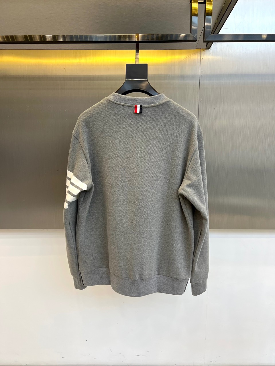 TB汤姆布朗、2025秋冬新品圆领卫衣，这款卫衣采用宽松休闲版型设计，左袖装饰四道白色条纹打造运动风尚。