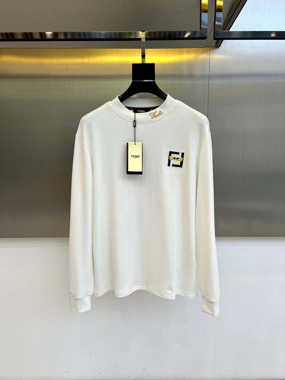 Fend芬迪、2025秋冬新品男士长袖T恤，以纯净白色诠释意式奢华美学。领口内侧饰有品牌标识，胸前点缀经