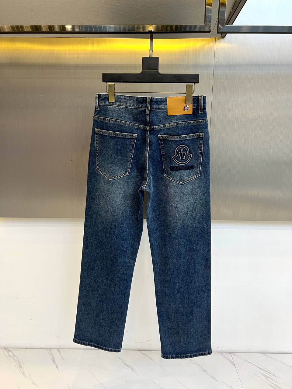 Mon蒙口、2025秋冬新品男士牛仔裤，以深蓝色水洗丹宁面料诠释奢华休闲美学。采用经典五袋式设计，裤腰饰