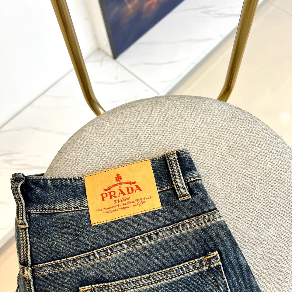 PRADA普拉、2025秋冬新品深蓝色牛仔裤，采用水洗工艺打造自然磨损与褪色效果，呈现复古质感。宽松版型