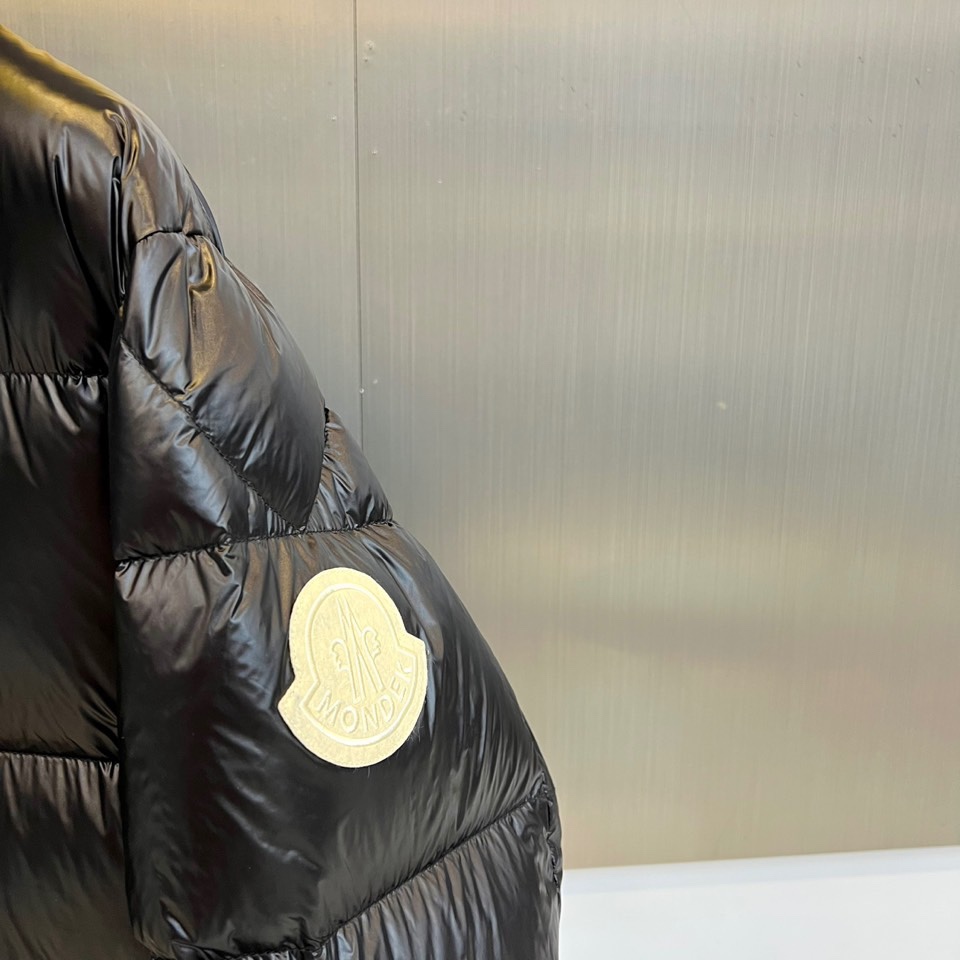 Mon蒙口、2025秋冬新品MONCLER曜黑机能羽绒服。本品以高光泽黑色锦纶面料打造科技质感，亮蓝色内