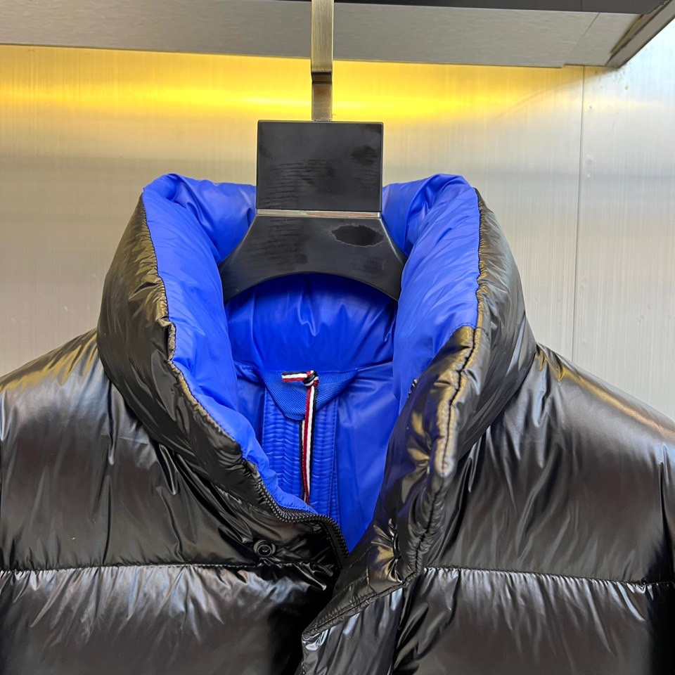Mon蒙口、2025秋冬新品MONCLER曜黑机能羽绒服。本品以高光泽黑色锦纶面料打造科技质感，亮蓝色内