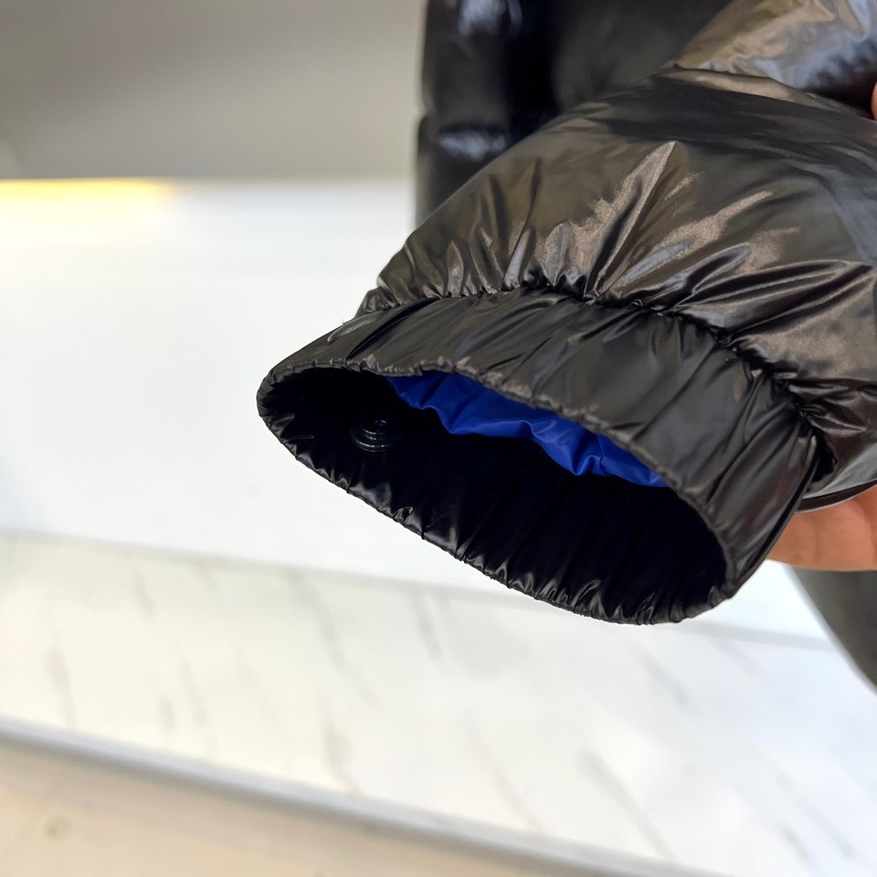 Mon蒙口、2025秋冬新品MONCLER曜黑机能羽绒服。本品以高光泽黑色锦纶面料打造科技质感，亮蓝色内