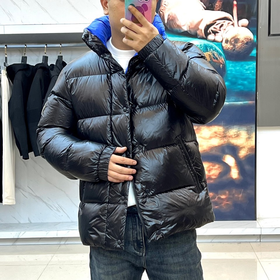 Mon蒙口、2025秋冬新品MONCLER曜黑机能羽绒服。本品以高光泽黑色锦纶面料打造科技质感，亮蓝色内