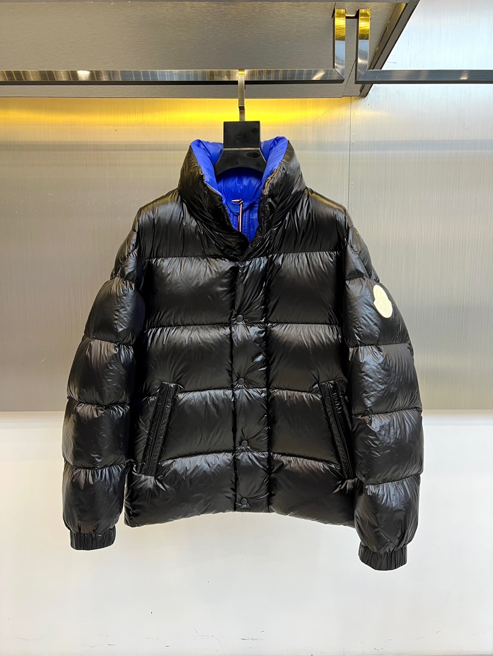 Mon蒙口、2025秋冬新品MONCLER曜黑机能羽绒服。本品以高光泽黑色锦纶面料打造科技质感，亮蓝色内